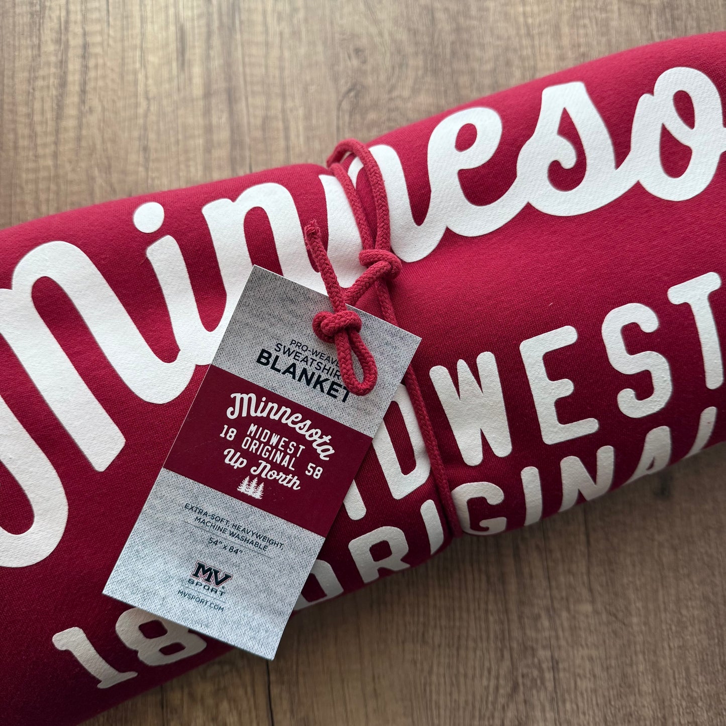 Red blanket with white text and a tag on a wooden surface