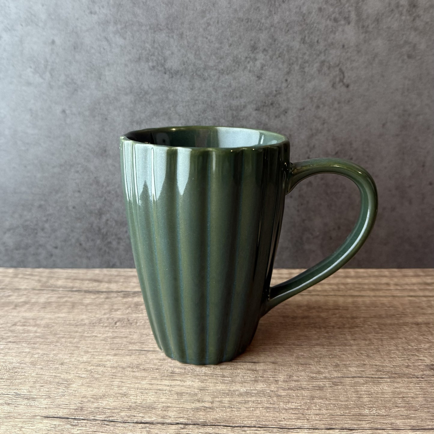 Green mug on a wooden surface with a gray background