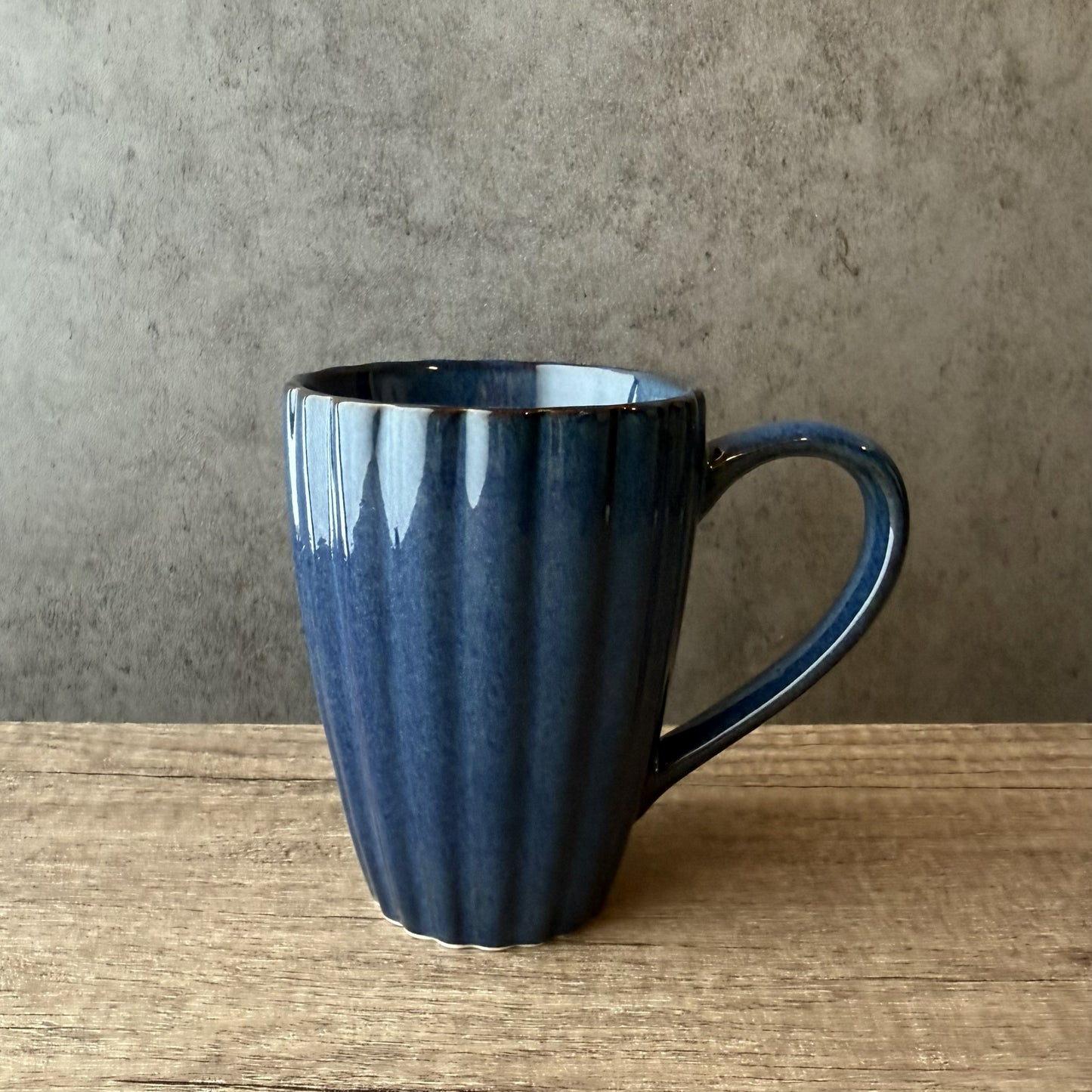 Blue ceramic mug on a wooden surface with a gray background