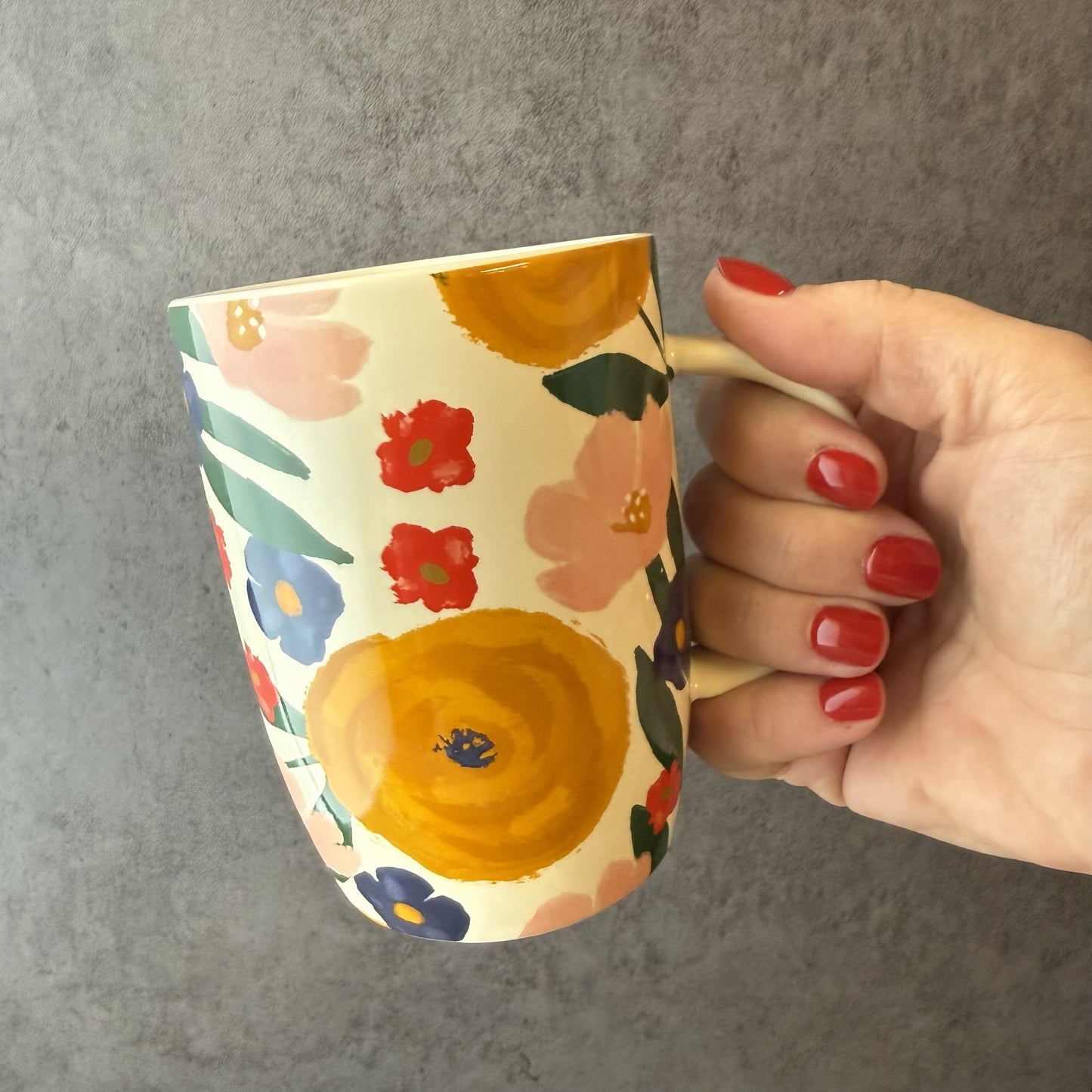 Floral-patterned mug on a wooden surface with a gray background