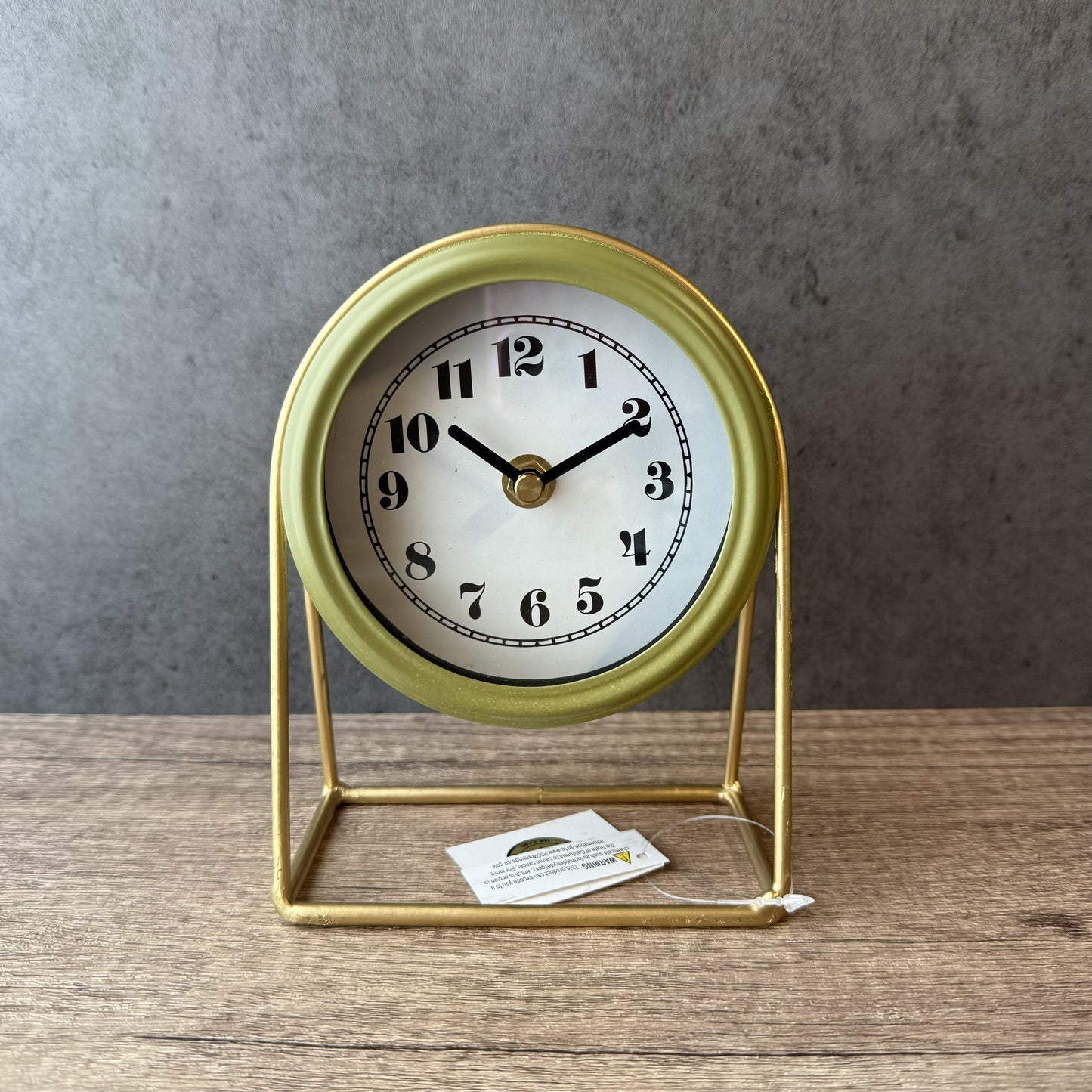 Gold-framed clock on a wooden surface with a gray background