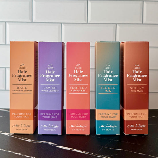 Five boxes of Luxe Hair Fragrance Mist on a tiled wall background