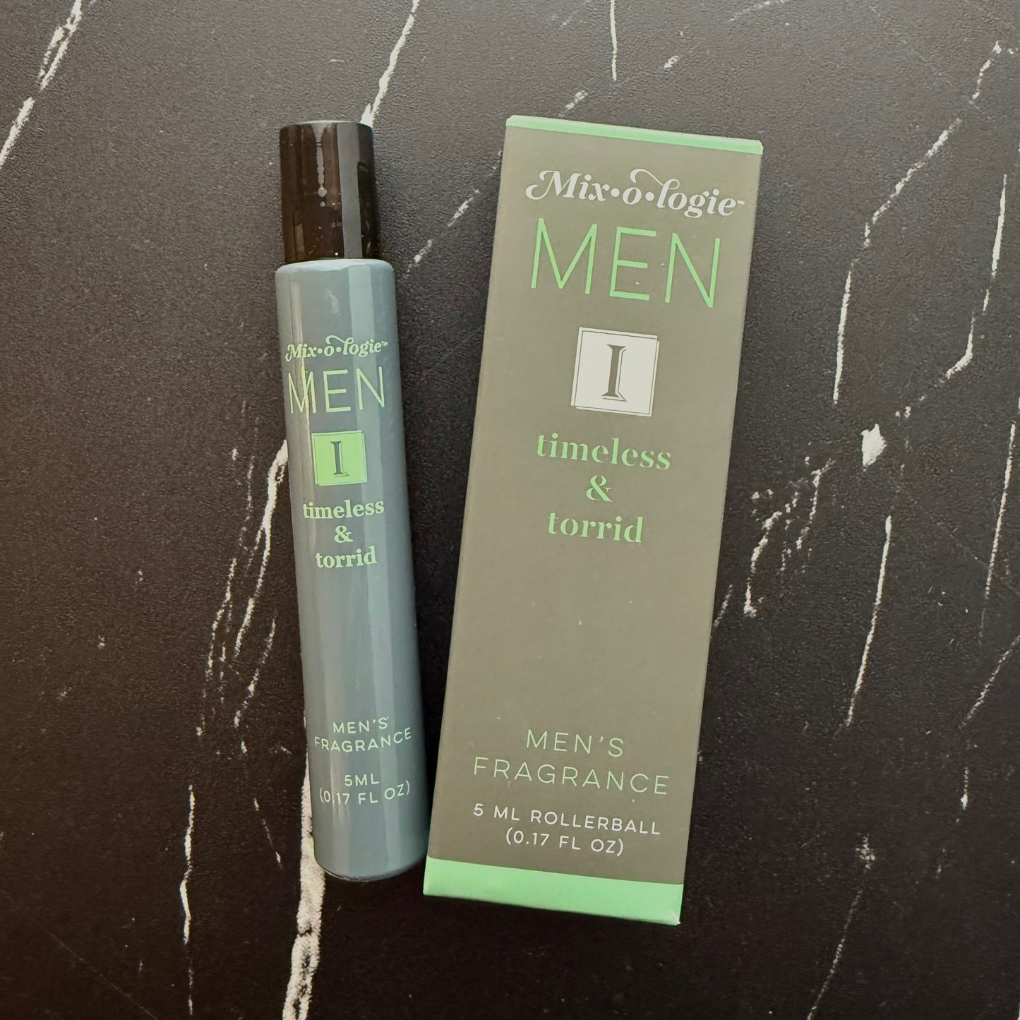 Men's fragrance rollerball and packaging on a dark marble surface