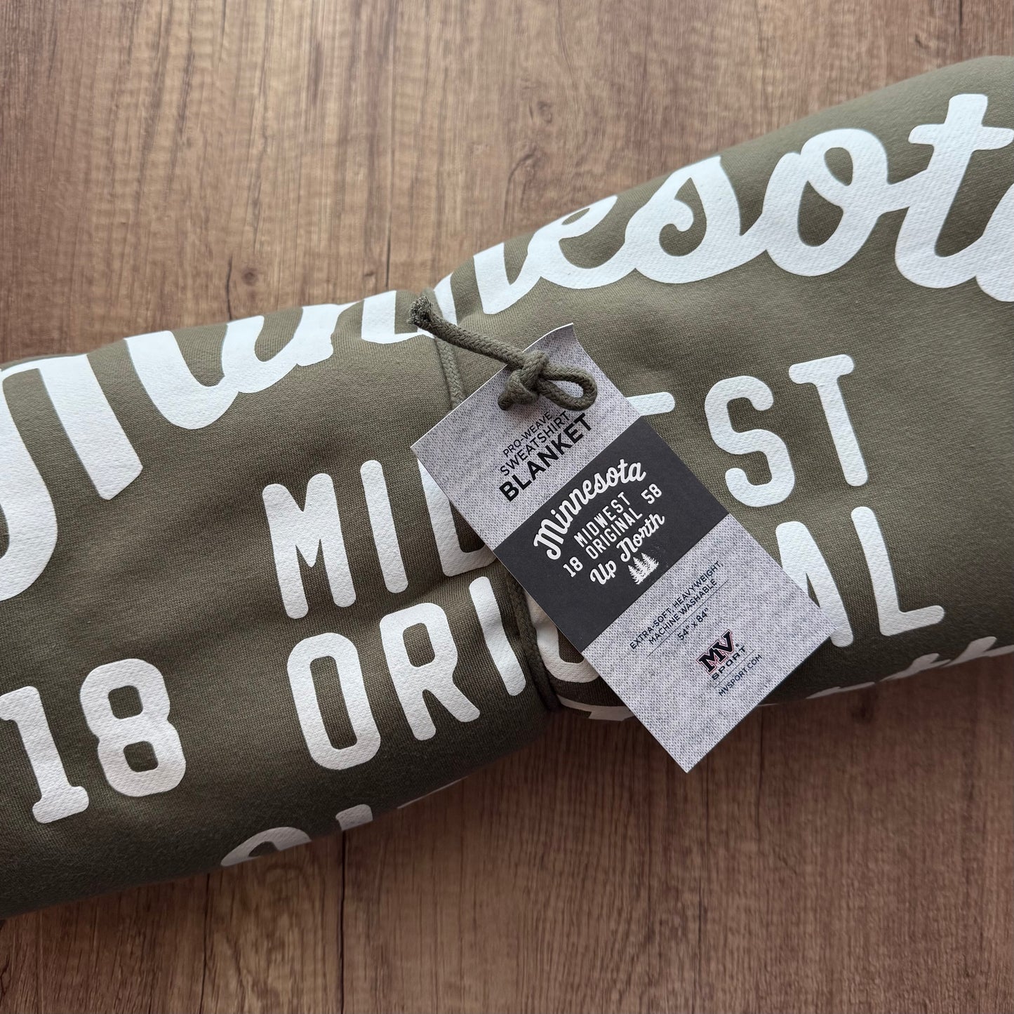 Rolled-up blanket with 'Minnesota' text and a tag on a wooden surface