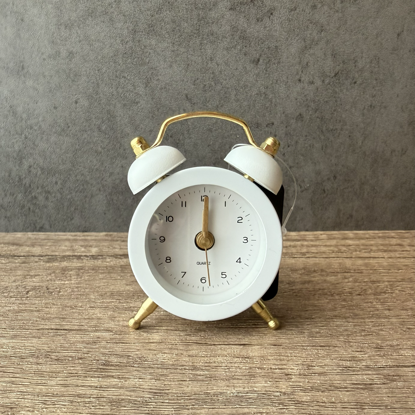White alarm clock with gold accents on a wooden surface