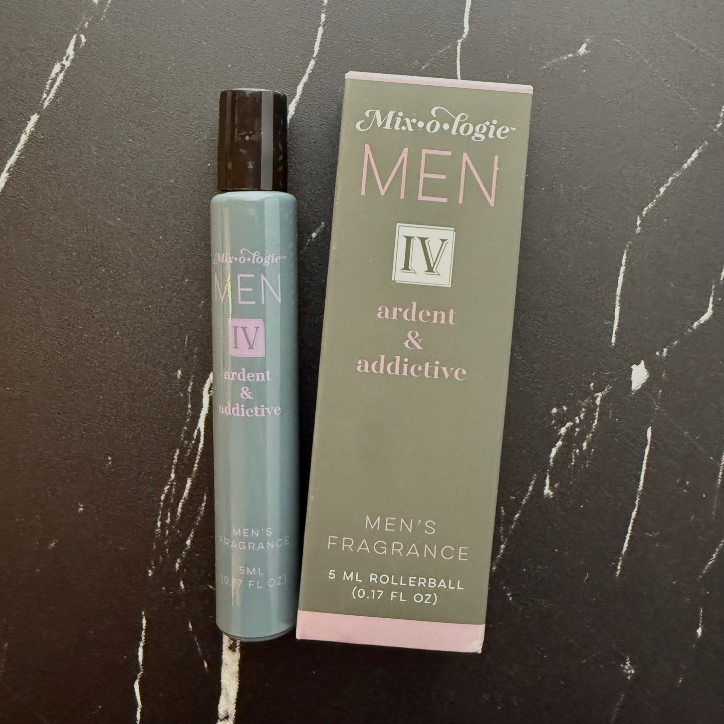 Men's fragrance rollerball and packaging on a dark marble surface