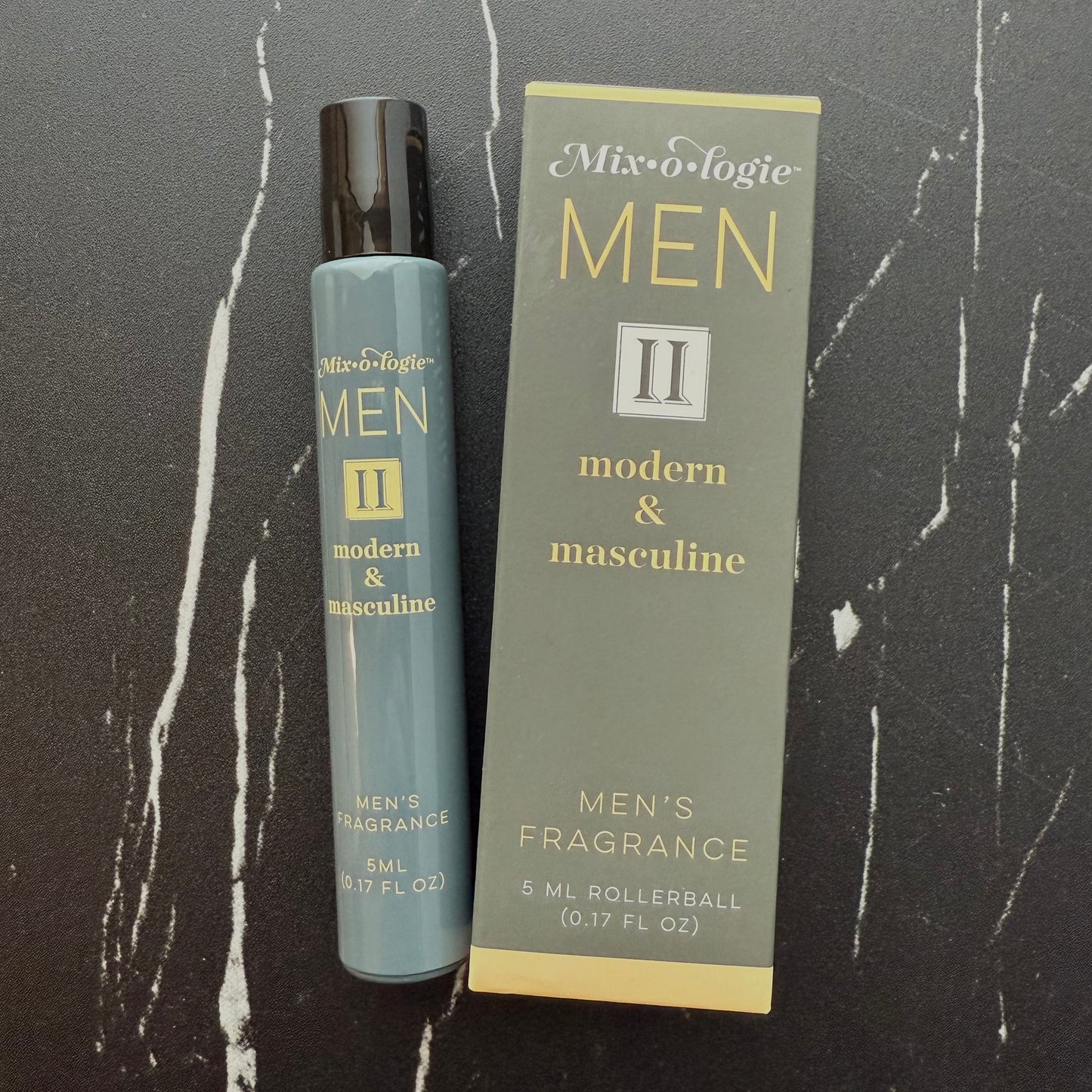 Men's fragrance rollerball and packaging on a dark marble surface