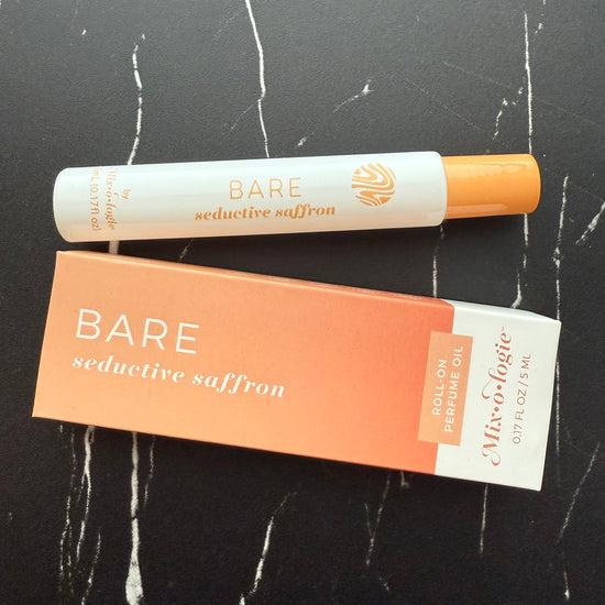 Bare seductive saffron perfume oil and packaging on a black marble surface