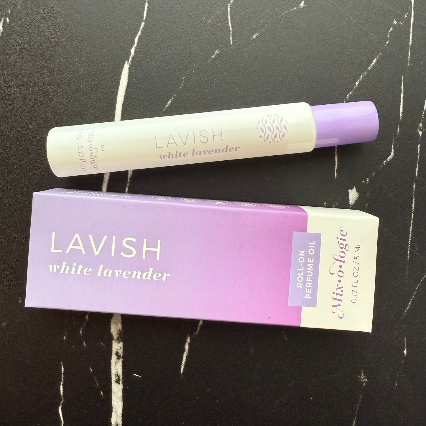 Lavish white lavender roll-on perfume oil with packaging on a black marble surface