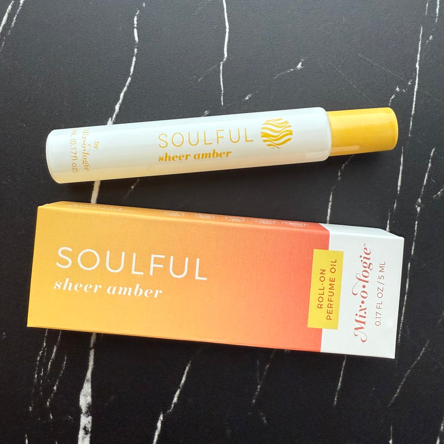 Soulful sheer amber roll-on perfume oil and packaging on a black marble surface