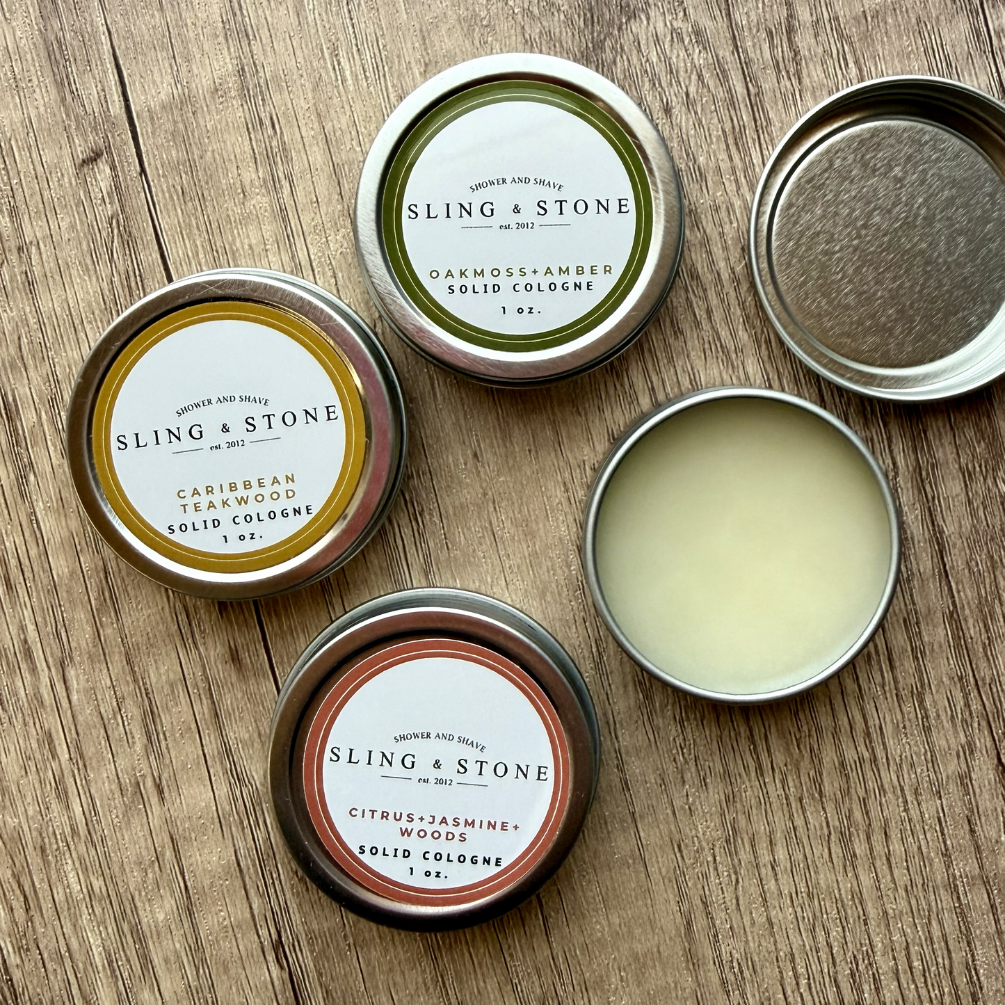Sling & Stone solid cologne tins on a wooden surface