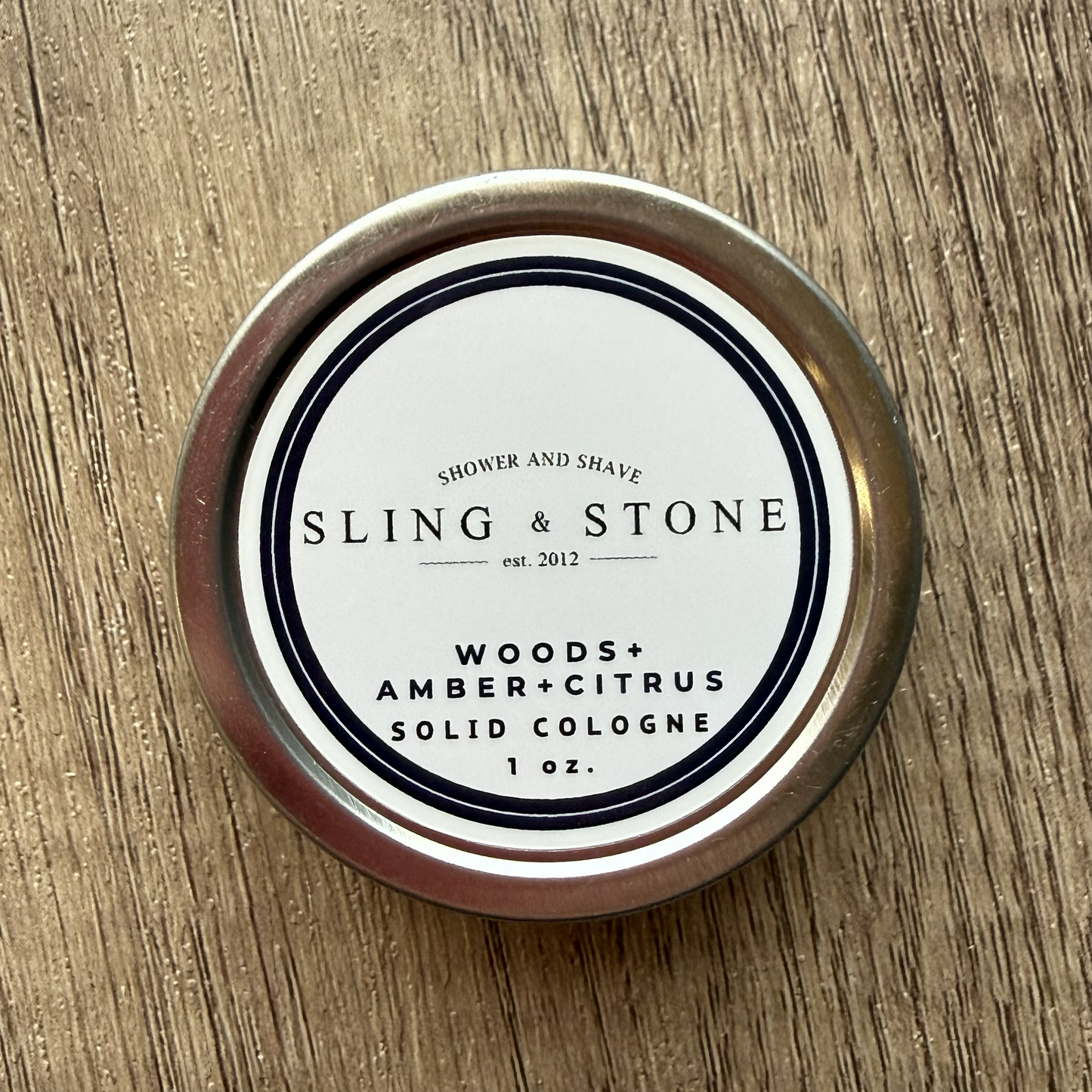 Solid cologne container with 'Sling & Stone' label on a wooden surface