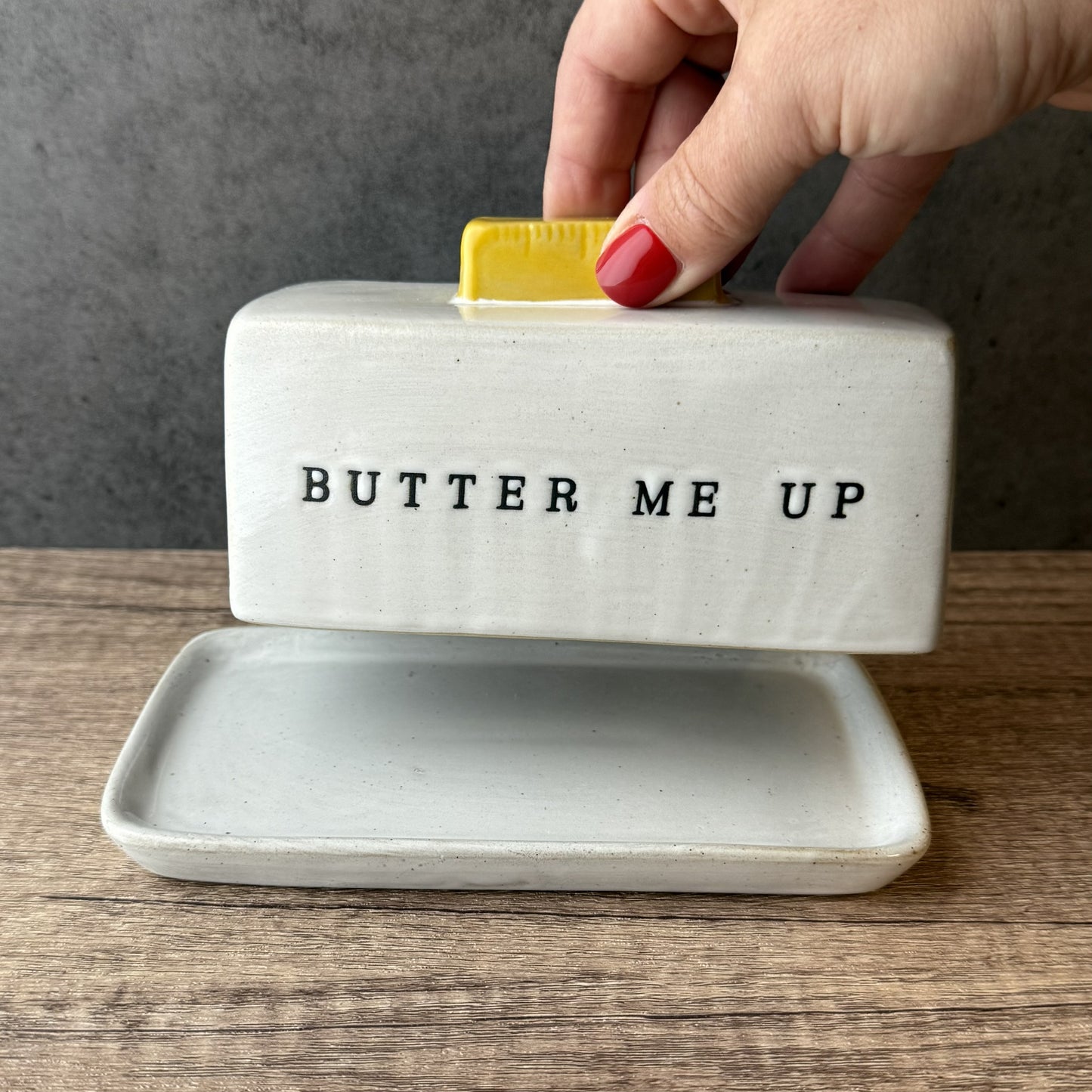 Butter dish with 'BUTTER ME UP' text on a wooden surface
