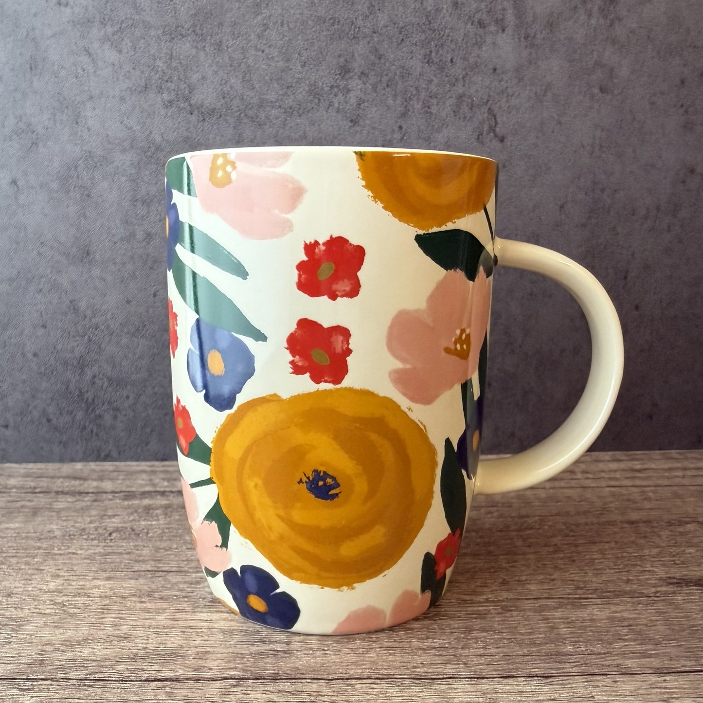 Floral-patterned mug on a wooden surface with a gray background