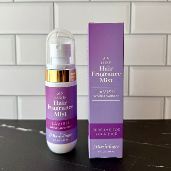 Hair fragrance mist bottle and packaging on a dark surface with a tiled wall background