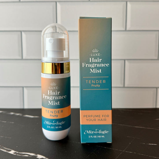 Hair fragrance mist bottle and packaging on a dark surface with a tiled wall background