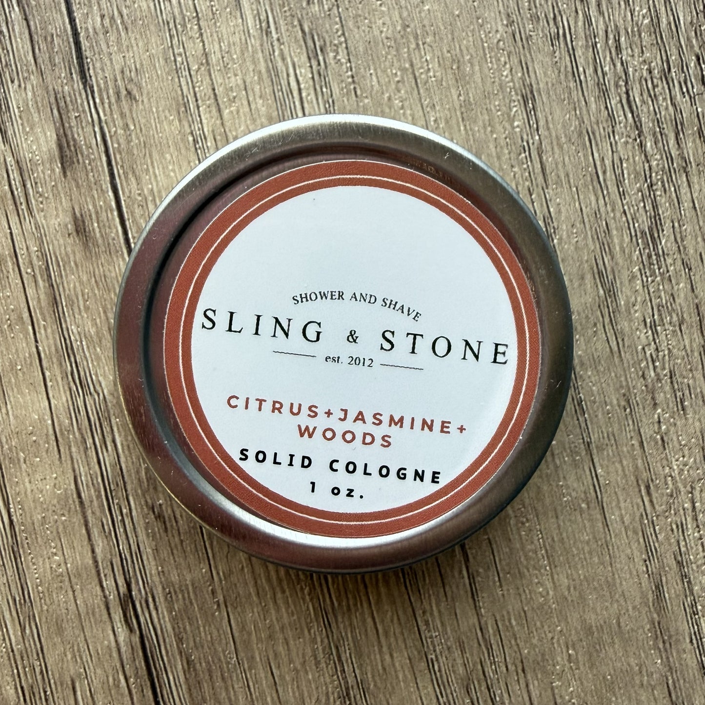 Sling & Stone solid cologne container on a wooden surface