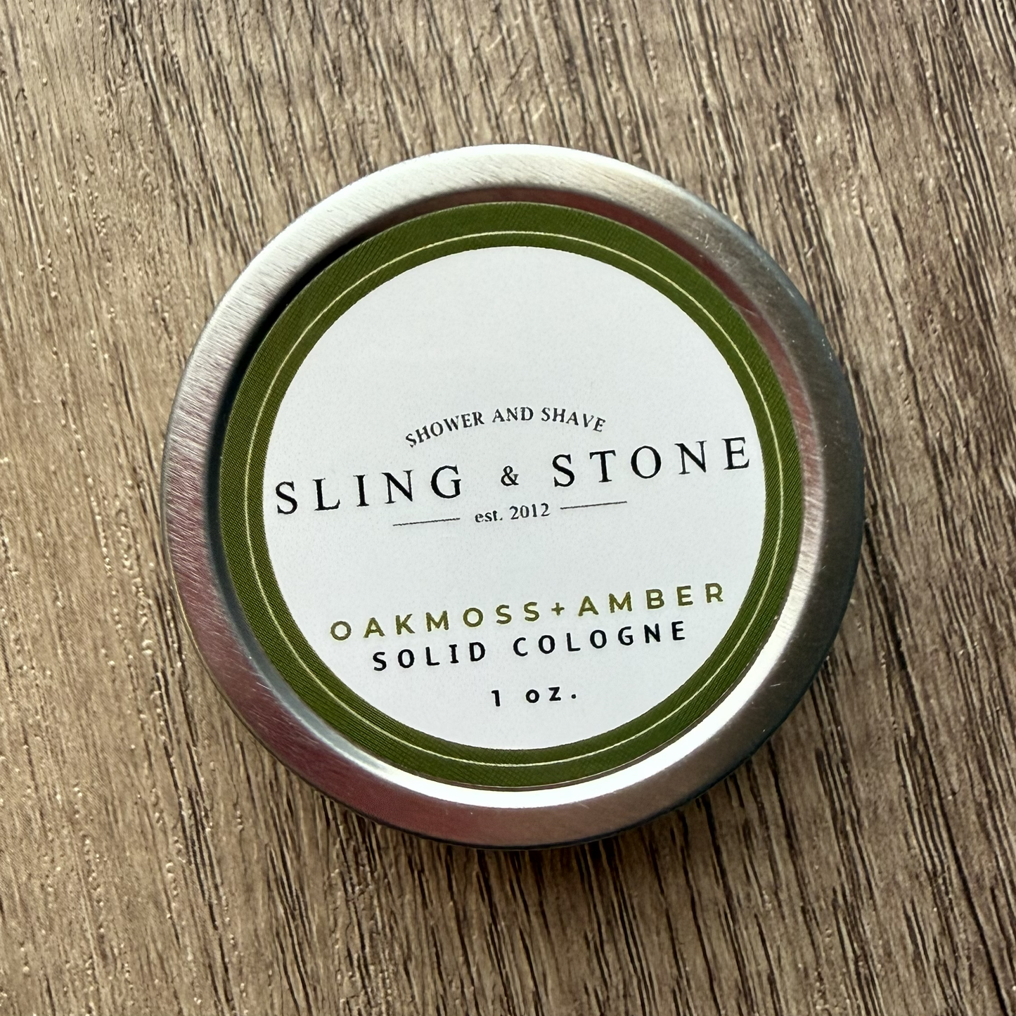 Sling & Stone solid cologne tin on a wooden surface