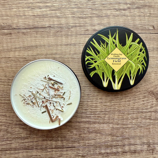 Two round containers on a wooden surface, one with a lid featuring lemongrass design.